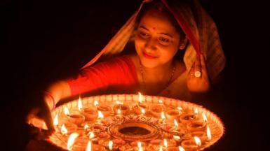A woman lights earthen lamps on the occasion of Diwali, the Hindu festival of lights, at her house in Guwahati on 24 October 2022