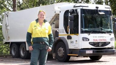 Woman standing in front of a garbage truck