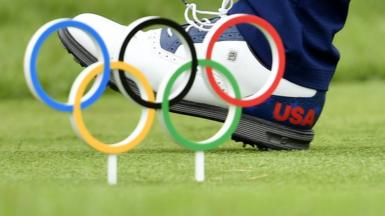A US golfer walks past a model of the Olympic rings embedded in the course at Tokyo 2020