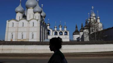 A woman walks past the Uspensky Cathedral in the town of Rostov in the Yaroslavl Region, Russia