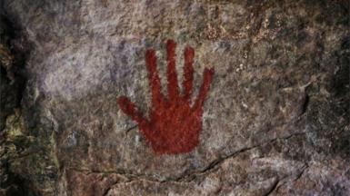 A red handprint on a cave wall.