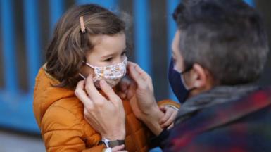Man helping girl with face mask