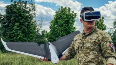 A Ukrainian soldier wearing virtual reality goggles prepares to launch a "Parrot" drone in a field