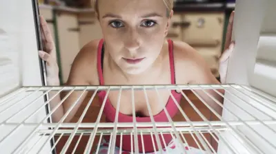 boş buzdolabına bakan kadın