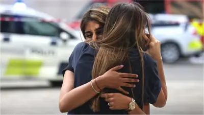 Two distressed women hug outside a Copenhagen shopping centre