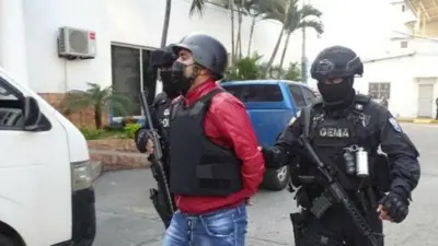 Norero marcha esposado custodiado por dos policías ecuatorianos.