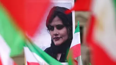 A portrait of Mahsa Amini stands between Iranian national flags