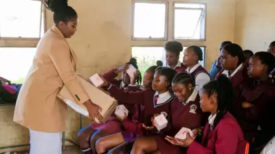 Tamara Magwashu distribue des serviettes hygiéniques à des élèves
