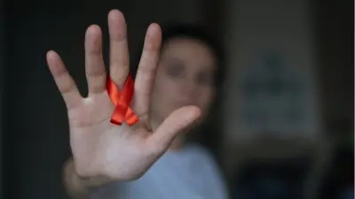 Mujer con el lazo rojo de la lucha contra el VIH/sida.