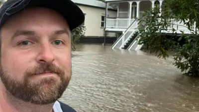 Sam pictured in a boat leaving his flooded house