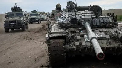 Ukraine military vehicles ride near a destroyed Russian tank in Izyum, eastern Ukraine