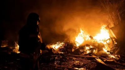 A firefighter works at a parking area damaged by suspected Russian missile debris in Kyiv on 16 May 2023