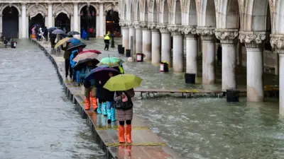 우산을 쓴 사람들이 다리를 건너고 있다