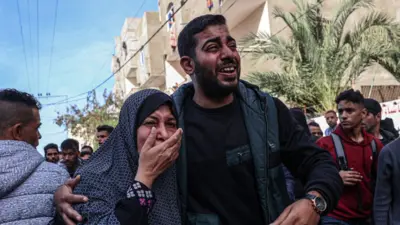 Palestinians react after a reported Israeli air strike hits a car in Rafah, southern Gaza