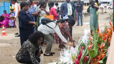 Des parents et des amis déposent des bougies et des fleurs pour les personnes disparues lors du naufrage d'un ferry, au port de Libreville, le 13 mars 2023.