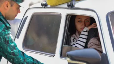 Азербайджанский военный проверяет автомобиль на выезде из Карабаха