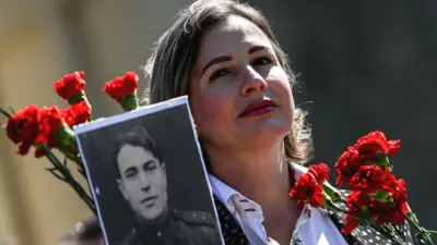 A woman holds a picture of Soviet Red Army veteran during Victory Day commemorations in Berlin, Germany, 9 May 2023