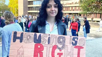 Студентка второго курса Даремского университета Рэйчел Лоуренс стоит с плакатом "Жилье - это наше право"