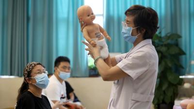 A doctor teaches fathers-to-be and mothers-to-be how to take care of newborns at Shijiazhuang Obstetrics and Gynecology Hospital before World Population Day on July 10, 2021 in Shijiazhuang, Hebei Province of China