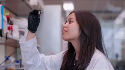 Denise Catacutan em laboratório segurando tubo de ensaio