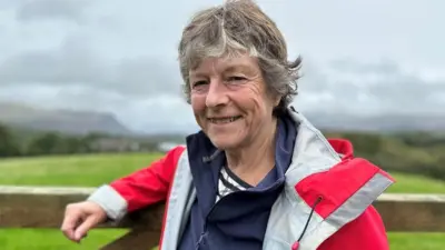 A woman in a red mountain rescue jacket smiles at the camera