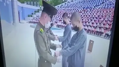 북한 보위부원들이 두 소년에게 수갑을 채우고 있다