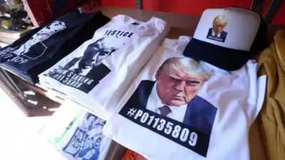 قمصان مع صورة دونالد ترامب أثناء توقيفه للمحاكمة