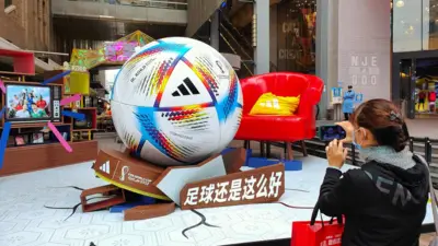 A woman takes a photo of a giant World Cup football in Shanghai, China