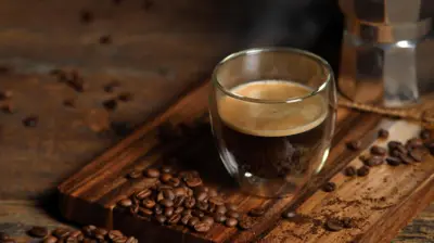 Una taza de café negro junto a granos de café.