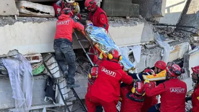 Rescatistas evacúan a una mujer que estaba bajo los escombros de un edificio que colapsó tras el terremoto en Kahramanmarash.