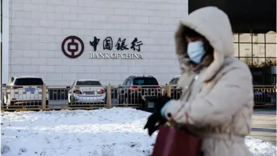 一名戴着口罩的女士走过北京中央商务区（2023年12月20日）。