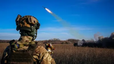 A Ukrainian soldier watches a rocket launcher firing towards Russian positions on the front line in eastern Ukraine in November