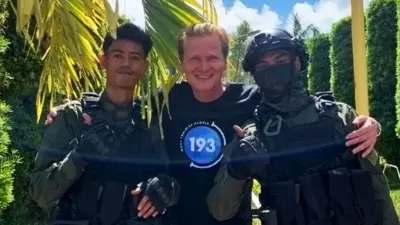 Kari-Matti smiles with two armed police officers