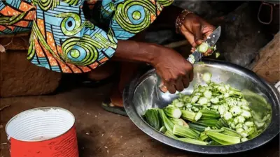 Une femme qui coupe du gombo
