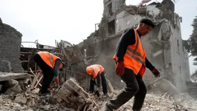 Emergency management specialists and volunteers remove the debris of a theatre building destroyed in the course of Ukraine-Russia conflict in the southern port city of Mariupol,
