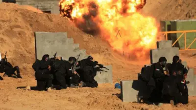 Homens treinando em terreno aberto com grandes armas e perto de explosão 