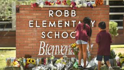 dos niños dejan flores en al escuela