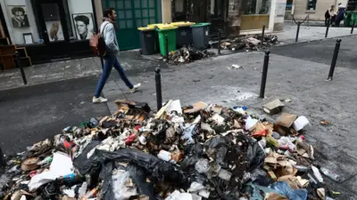 A man walks past a burnt store and damages in a street the day after clashes during protests over French government's pension reform in Paris, France, March 24, 2023.