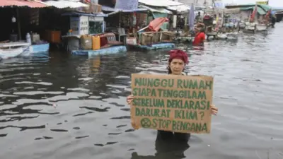 Aktivis lingkungan memprotes dampak perubahan iklim di tengah banjir rob di kawasan Muara Angke, Jakarta Utara pada Selasa, 7 Desember 2021.