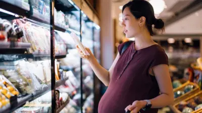 Mulher grávida olhando produto em supermercado