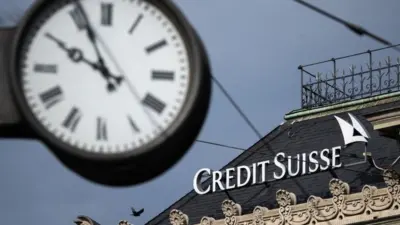 A clockface pictured in front of a Credit Suisse building