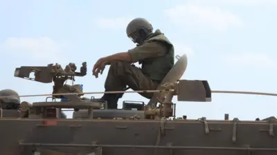Un soldado israelí sentado sobre un tanque en la frontera con Gaza