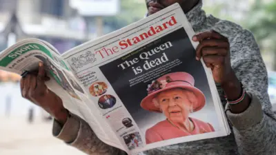 Un vendeur de journaux lisant un quotidien local relatant le décès de la reine Elizabeth II, à Nairobi.