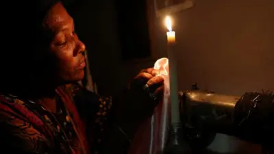 La couturière Faieza Caswell de Mitchells Plain coud à la lumière des bougies sur son lieu de travail, sur les Cape Flats, en raison des coupures de courant régulières de la compagnie d'électricité sud-africaine Eskom, appelées "délestage", au Cap, en Afrique du Sud, le 11 février 2023.
