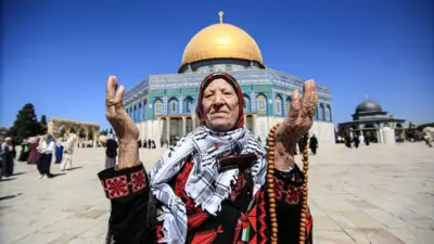Молящаяся женщина на фоне мечети