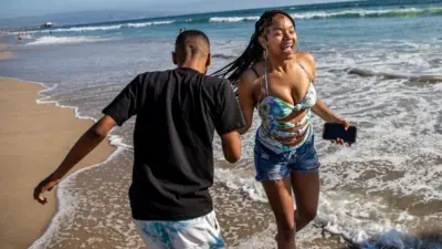 Una joven pareja afrodescendiente celebra la recuperación de la playa