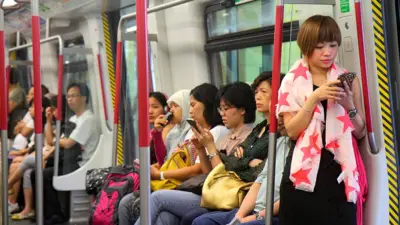 Hong Kong MTR Subway, Airport Express Asian woman checking smartphone.