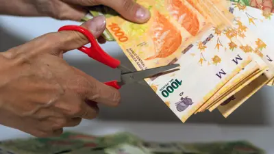 Una persona cortando billetes de 1000 pesos argentinos