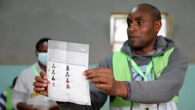 An elections official displaying a ballot paper during counting