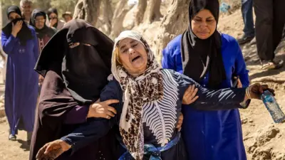 Une femme est aidée alors qu'elle réagit à la mort de membres de sa famille au sud-ouest de Marrakech.